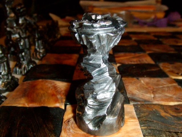 A single silver bishop with a twisted surface on a wood-grain square.