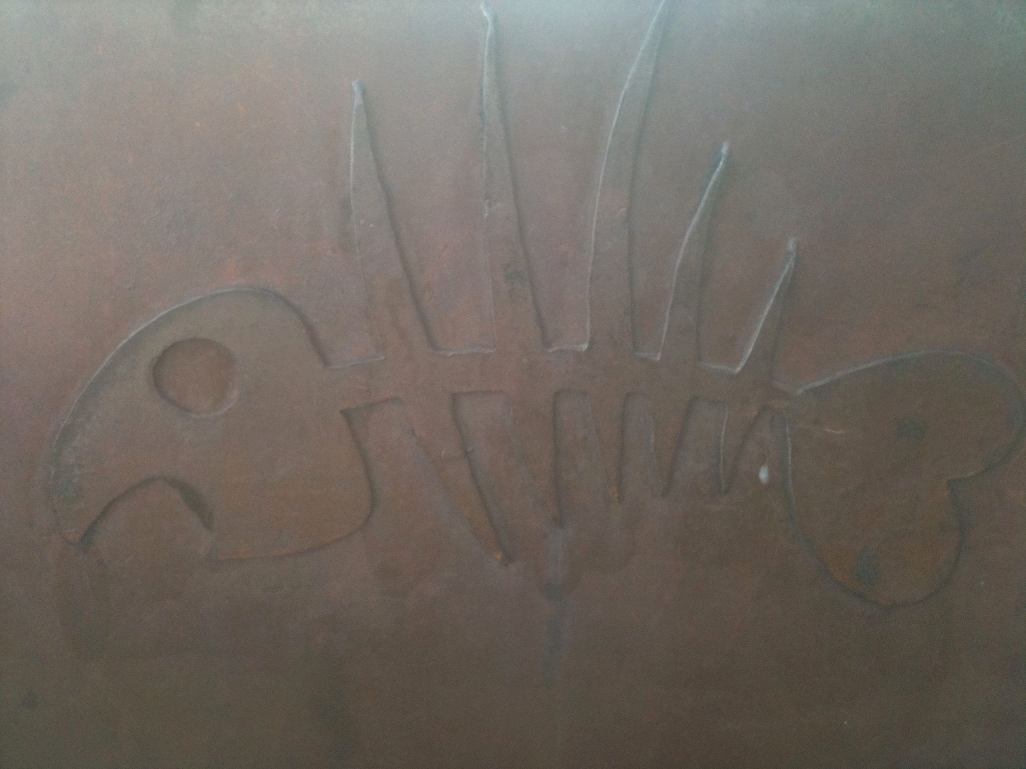 Close view of a steel door panel with a fish skeleton raised in its surface.